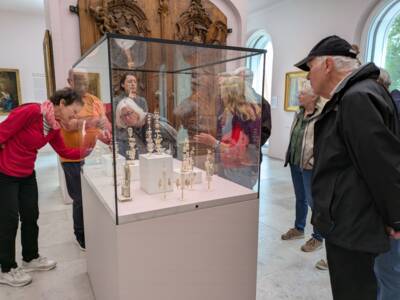 Delegation aus Meylan besichtigt Exponate in einem Schaukasten im Diözesanmuseum Freising im Mai 2026